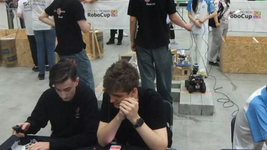 Die beiden Operateure sitzen mit dem Rücken zum Parcours, auf dem der CJT-Roboter seine Aufgaben erledigt.